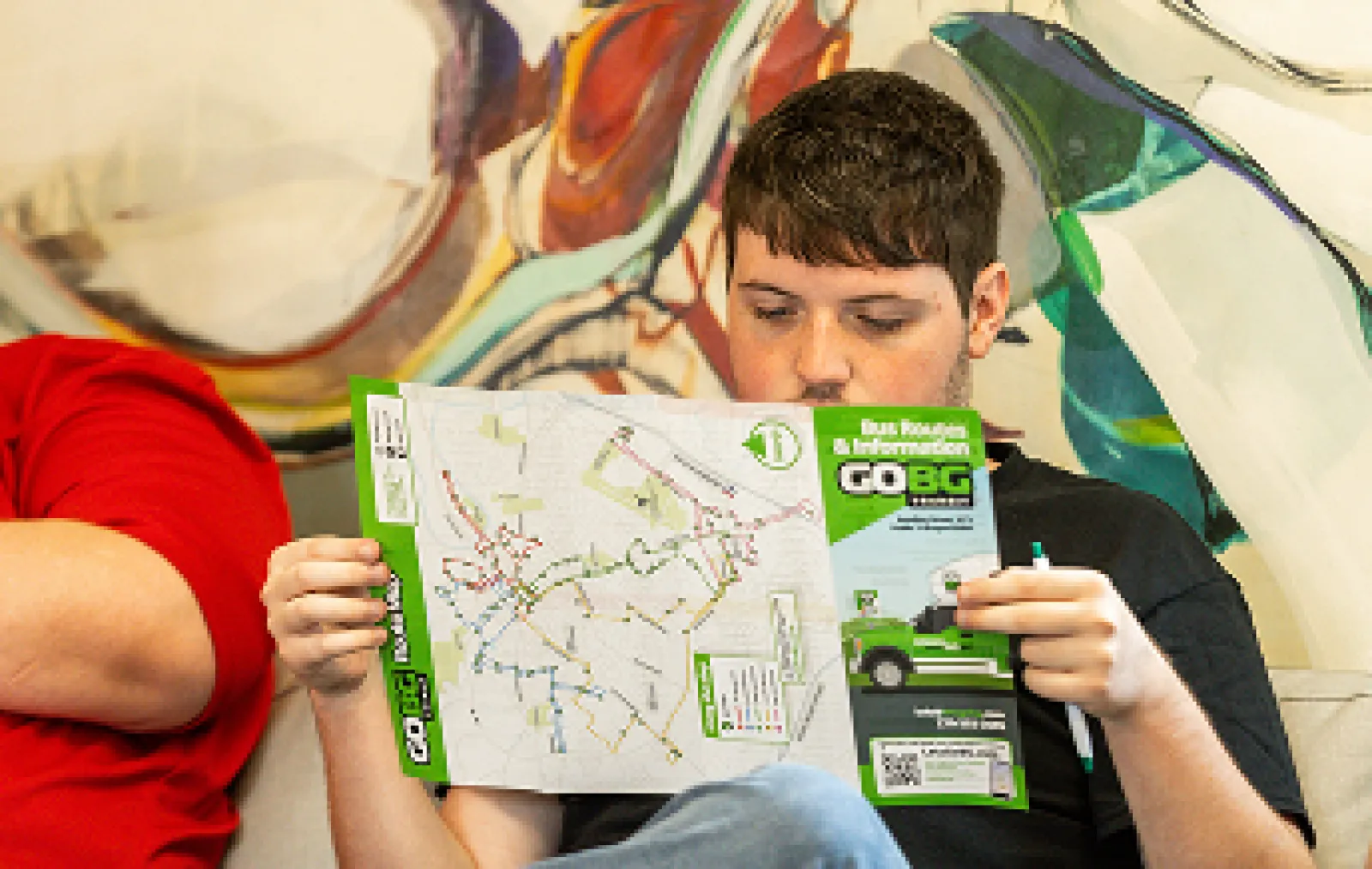 LifeWorks participant reading a GoBG Transit brochure on a couch