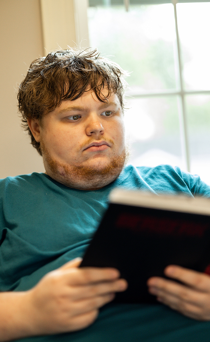 LifeWorks participant reading a book in front of a window.