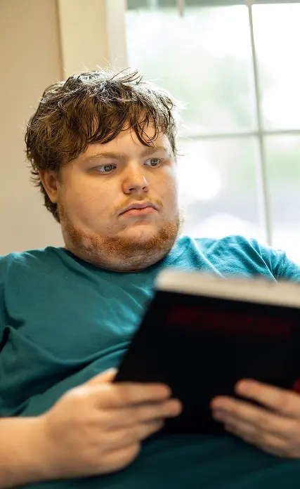LifeWorks participant reading a book in front of a window.