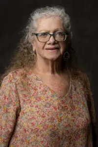 Julie Boca smiling on a dark background for a headshot photo