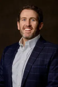 George Bowra smiling in a headshot on a dark background