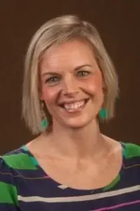 Heidi Johnson headshot on dark red background smiling at the camera.