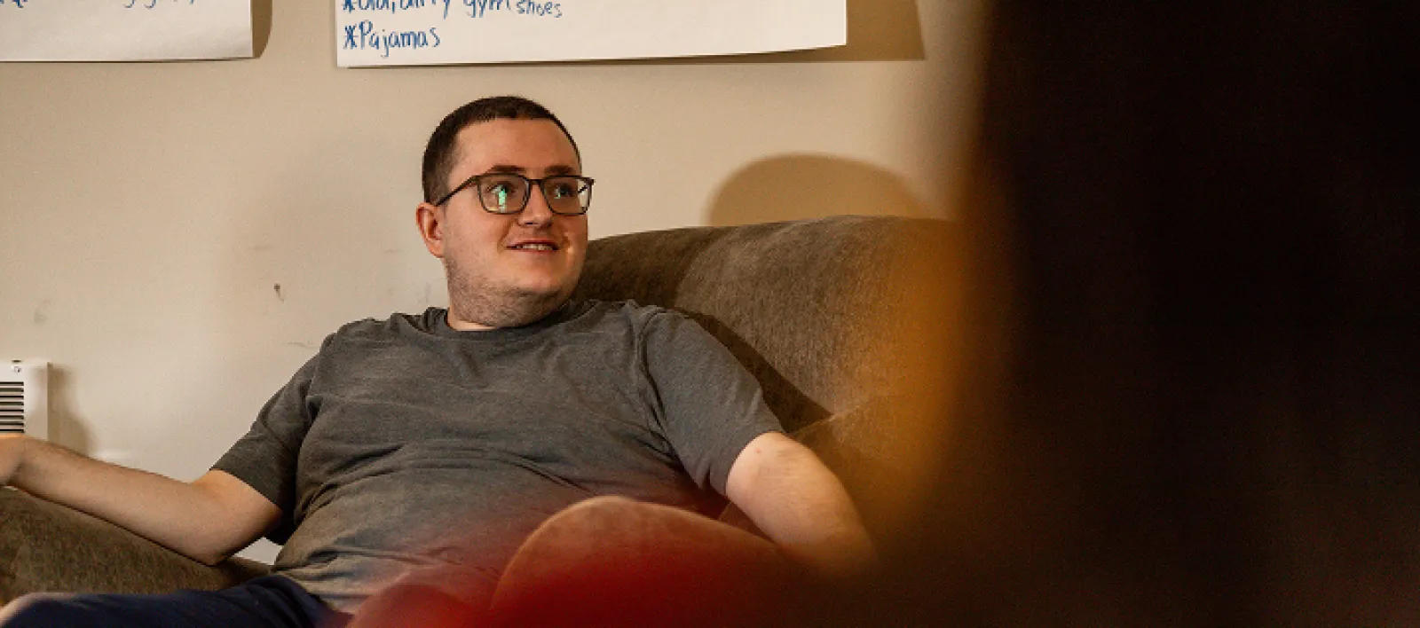 Male smiling while seated in a brown chair in a LifeWorks apartment.