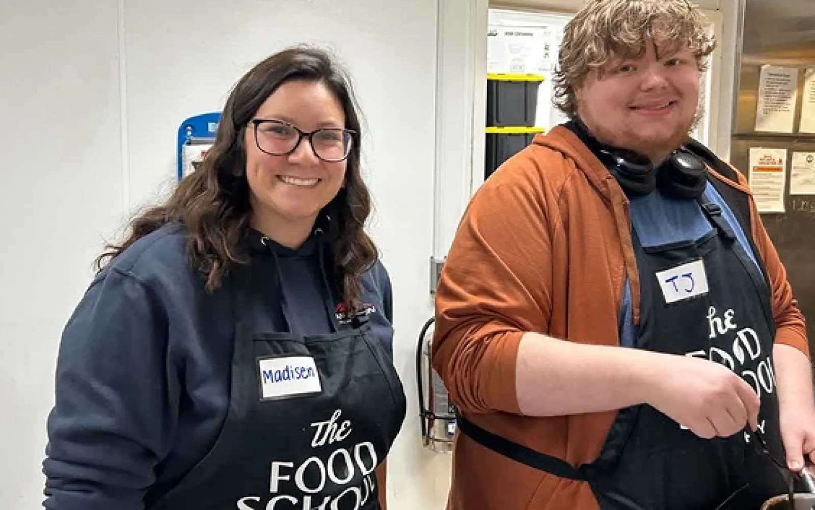 A LifeWorks staff member and participant are smiling direct to camera while preparing food in a cooking class.