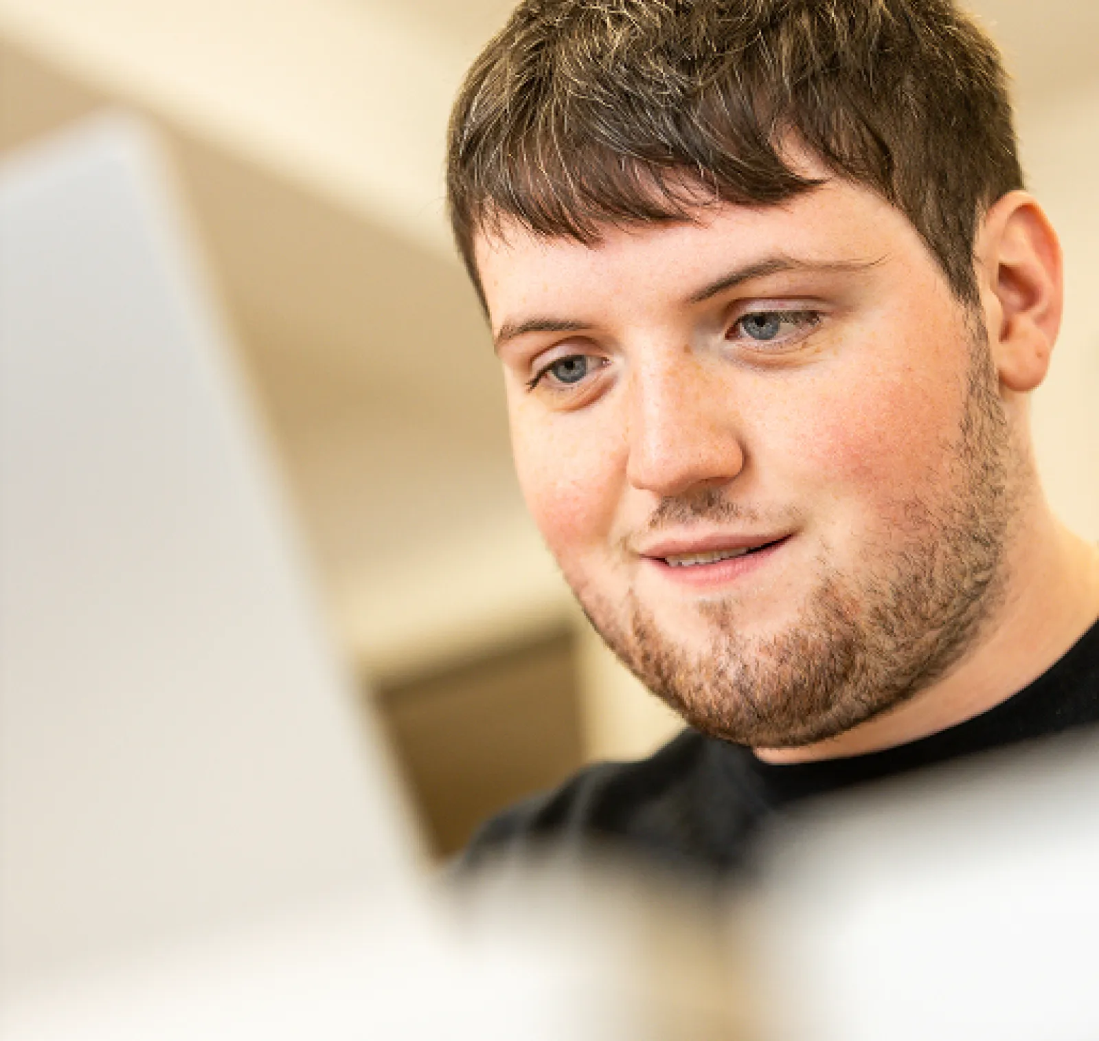 A happy LifeWorks participant smiles at his laptop screen.